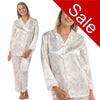 ivory background with a peach/pink floral print silky shiny satin pjs set consisting of a shirt style top with full length sleeves, a collar, top pocket and a button up front with matching full length trousers in UK sizes 10, 12, 14