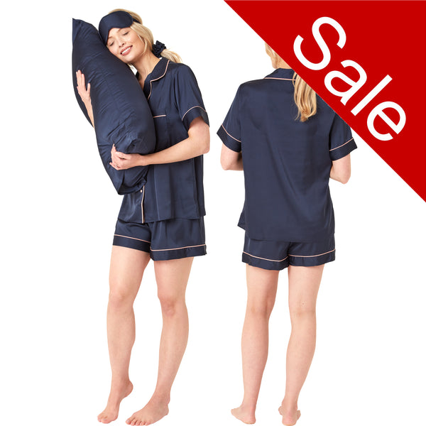 Plain dark navy blue matt satin pjs set consisting of a shirt style top with a collar, top pocket and button up front and short sleeves with matching shorts with an elasticated waist band. The pjs also come with a matching pillow case, eye mask and bobble. In UK size 14, 16, 18, 20