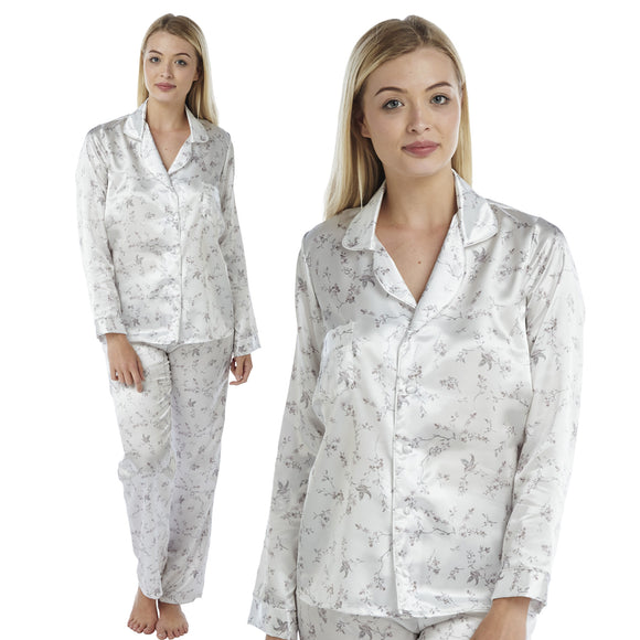 ivory background with a purple floral and hummingbird print silky shiny satin pjs set consisting of a shirt style top with full length sleeves, a collar, top pocket and a button up front with matching full length trousers in UK sizes 8, 10, 12, 14