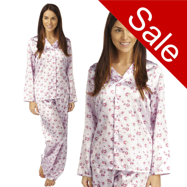 pink background with a darker pink poppy floral print silky shiny satin pjs set consisting of a shirt style top with full length sleeves, a collar, top pocket and a button up front with matching full length trousers in UK sizes 12, 14