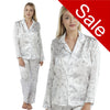 ivory background with a purple floral and hummingbird print silky shiny satin pjs set consisting of a shirt style top with full length sleeves, a collar, top pocket and a button up front with matching full length trousers in UK sizes 8, 10, 12, 14
