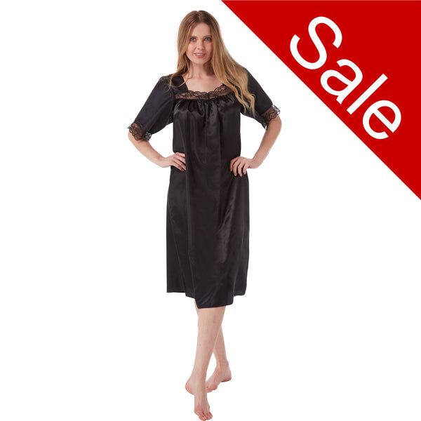 plain black shiny silky satin classic style mid length nightdress which is straight in fit with gathered fabric to the chest and elbow length sleeves. The chest and sleeves are trimmed with floral lace and it it available in UK sizes 8, 10, 12, 14, 16, 18, 